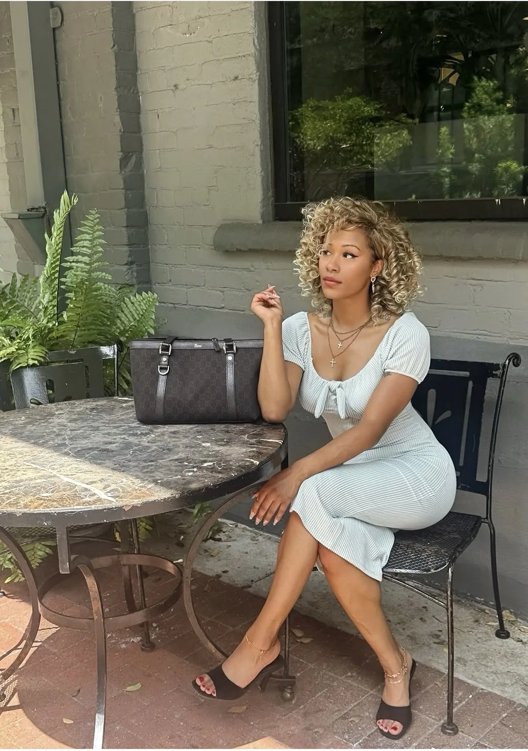 B’Chelle seated outdoors in a pale blue dress